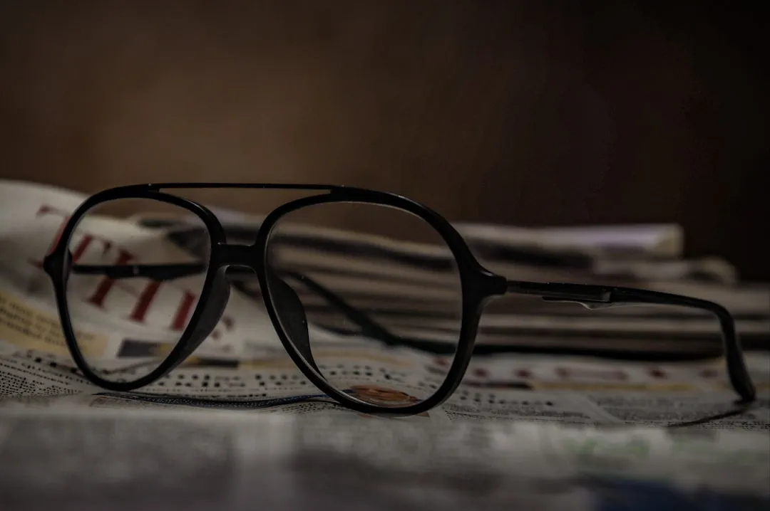 Newspaper obituary page with reading glasses on a desk